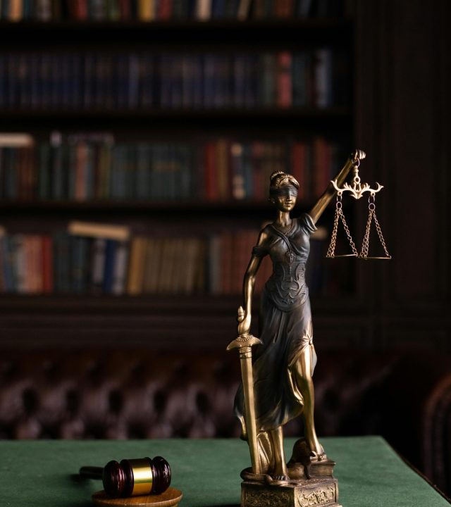 Lady Justice and gavel on a table in a classic law library setting.